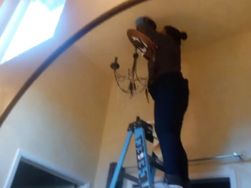 Electrician installing a chandelier in a Urbana residence